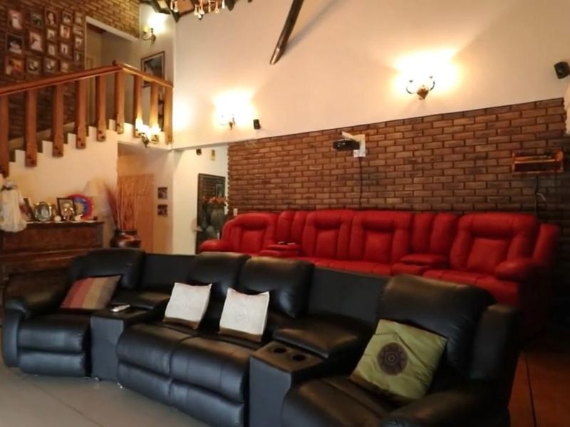 A dedicated cinema room featuring an exposed brick feature wall, wall-mounted projector, and a timber staircase with a matching balustrade.