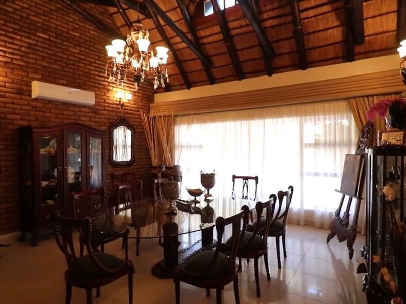 Spacious dining room featuring exposed brick walls, high vaulted timber ceilings with thatch detail, and large windows allowing for ample natural light.