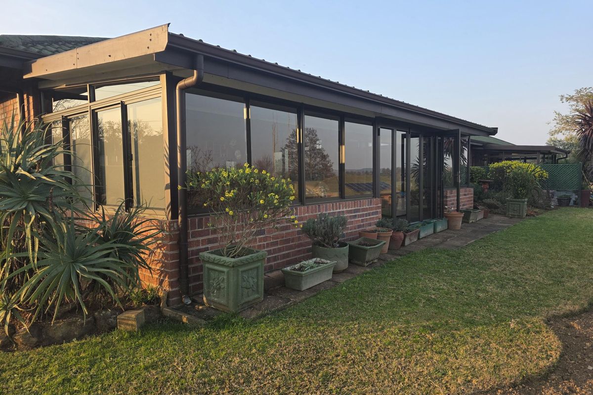 Rear view of the townhouse featuring a brick facade, extensive glass sliding doors, and a paved walkway leading along the garden.
