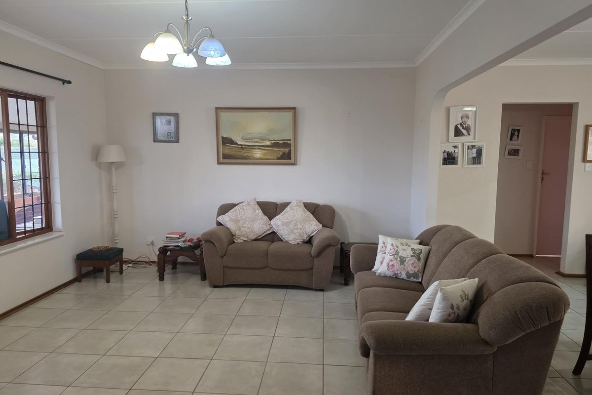A spacious living room featuring neutral ceramic floor tiles, coved ceilings, and an arched entryway leading to adjacent areas.