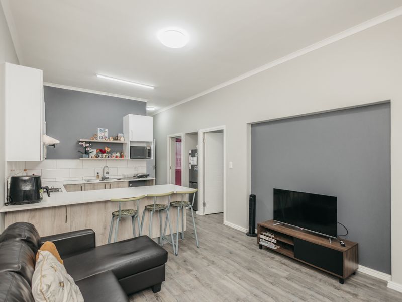 Modern open-plan living area featuring a functional kitchen with island seating, subway tile backsplash, and durable laminate flooring throughout the space.