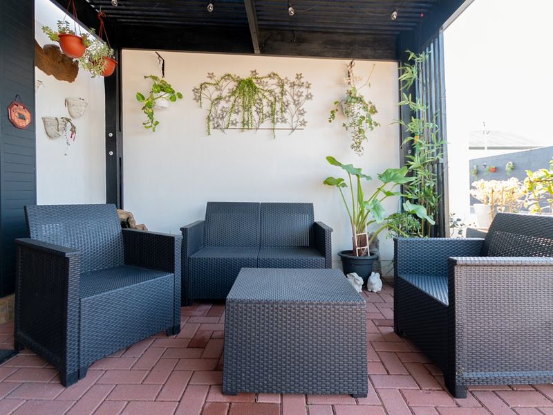 A covered outdoor patio area featuring a dark timber pergola and red brick paving, providing a comfortable space for outdoor relaxation.