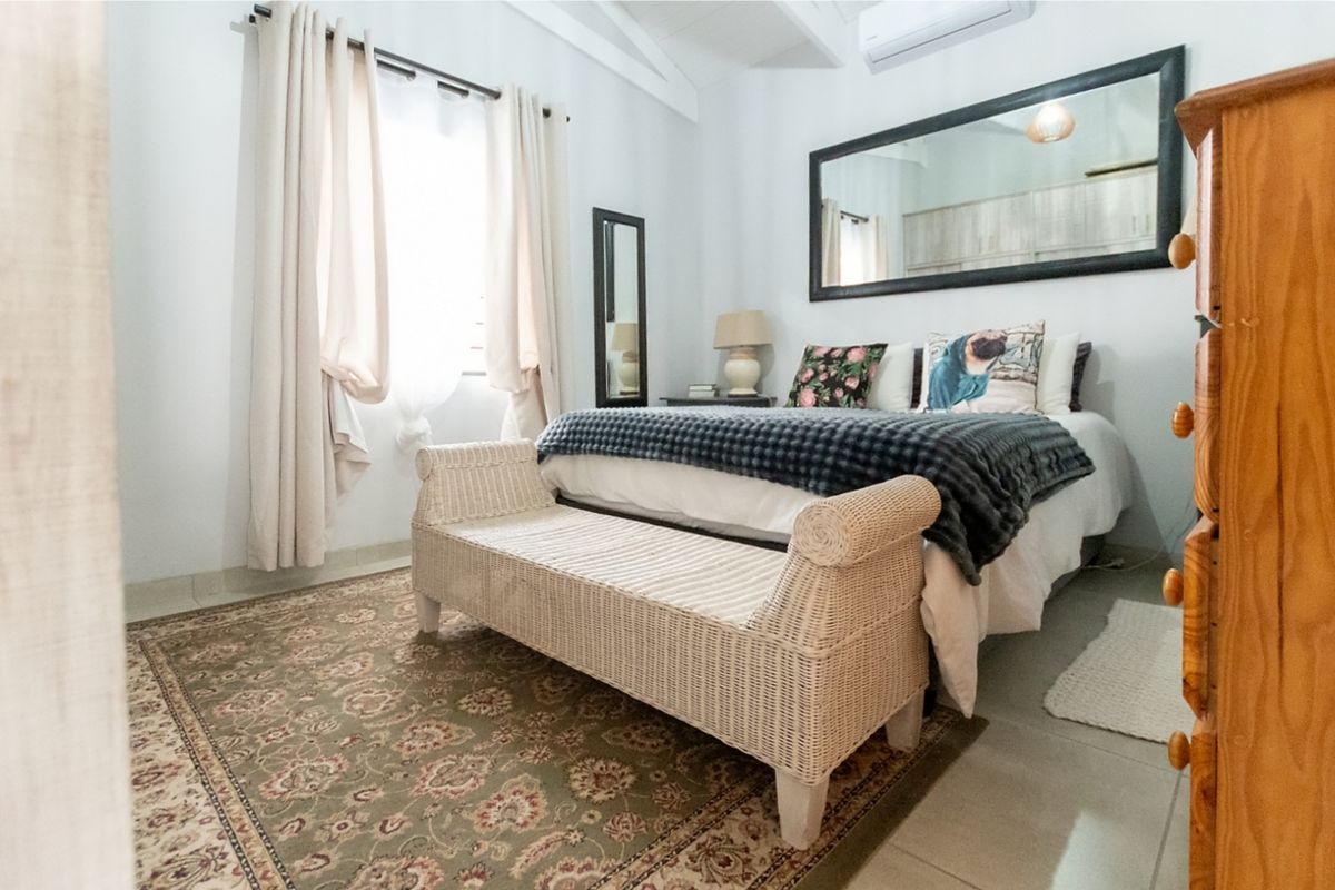 A well-maintained bedroom featuring a vaulted ceiling, tiled flooring, and a wall-mounted split-system air conditioning unit.