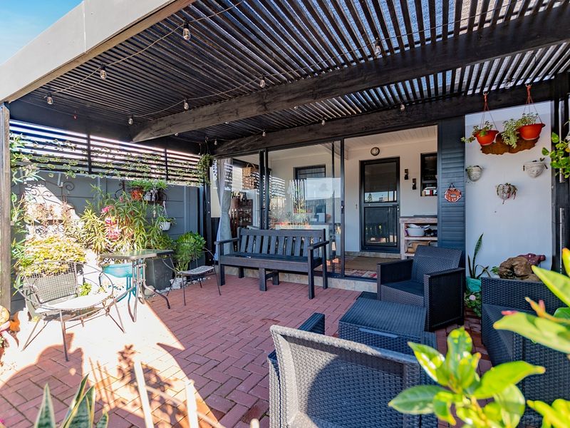 A well-maintained outdoor patio area featuring brick paving and a covered timber pergola, providing a comfortable space for outdoor relaxation.