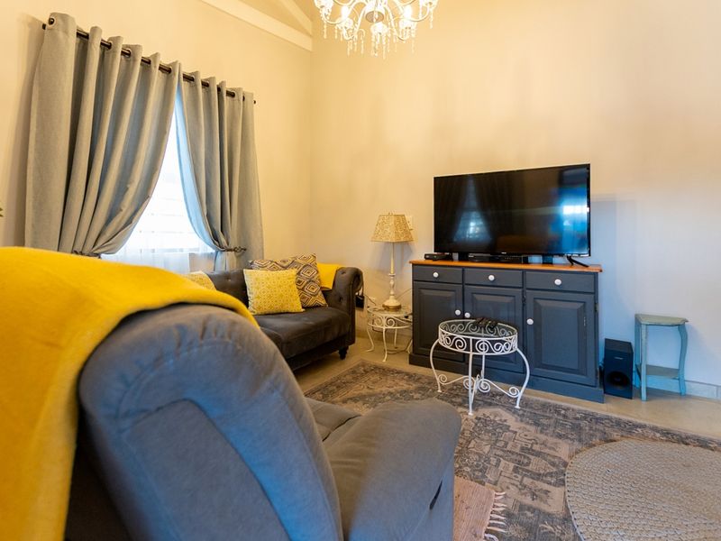 A cozy living room featuring a vaulted ceiling, neutral walls, and tiled flooring, providing a comfortable and inviting space.