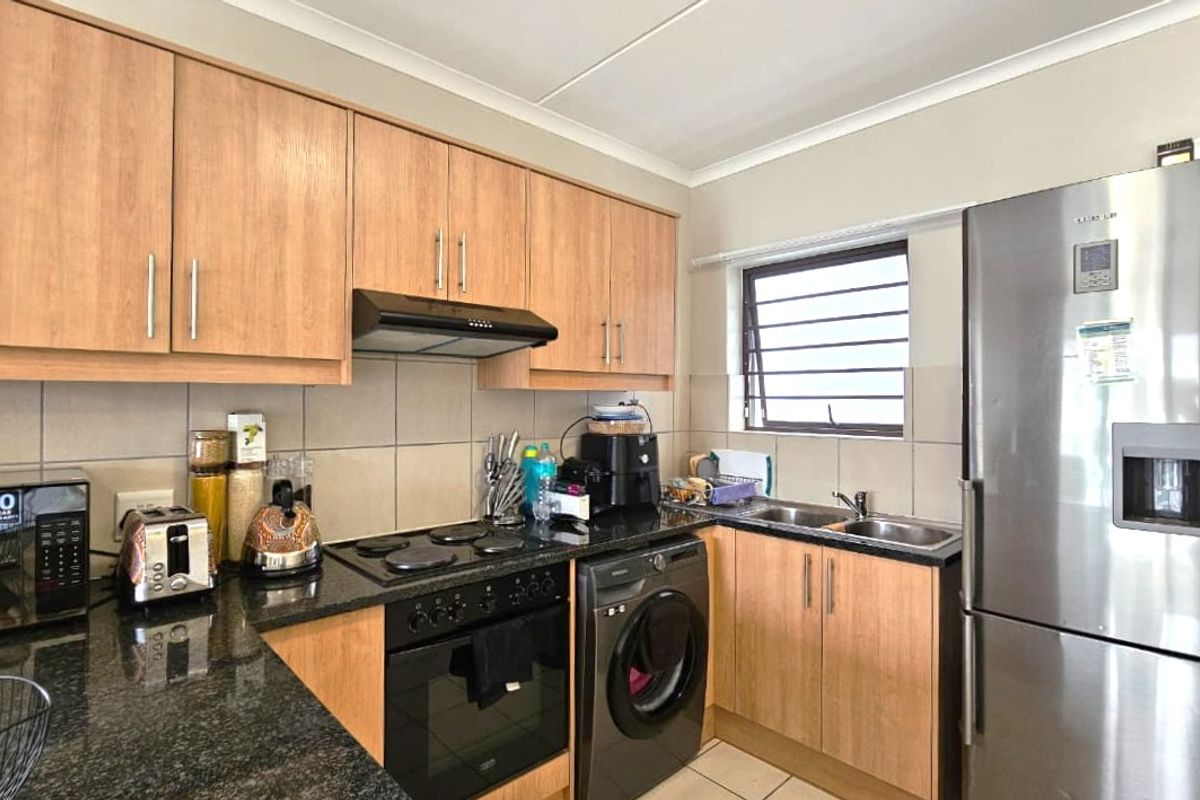 Functional kitchen featuring laminate cabinetry, granite countertops, built-in oven, electric hob, extractor fan, and a double stainless steel sink with tiled backsplash.
