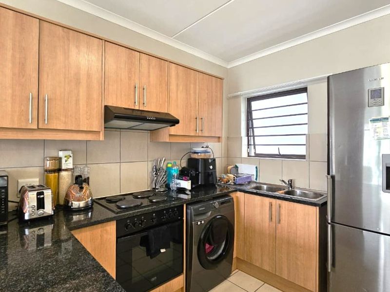 Functional kitchen featuring laminate cabinetry, granite countertops, built-in oven, electric hob, extractor fan, and a double stainless steel sink with tiled backsplash.