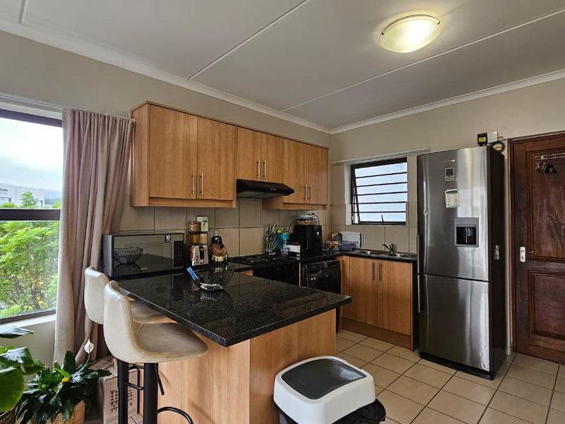 Functional kitchen featuring granite countertops, laminate cabinetry, tiled flooring, and a breakfast nook, offering a practical layout for daily meal preparation.