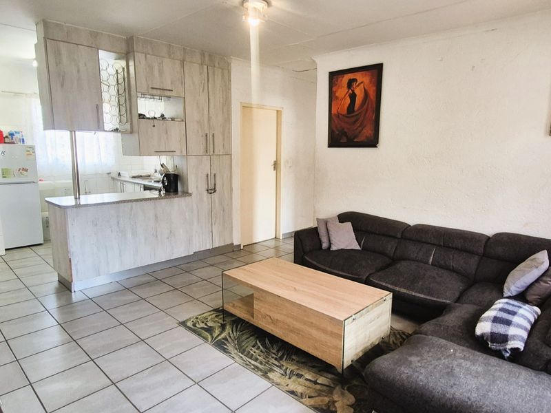 Open-plan living area featuring tiled flooring and a functional kitchen with built-in cabinetry and a breakfast counter.