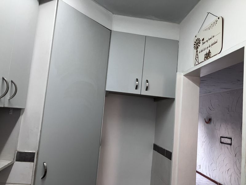 A functional kitchen area featuring built-in grey cabinetry and tiled splashbacks, offering a clean and neutral space for culinary activities.