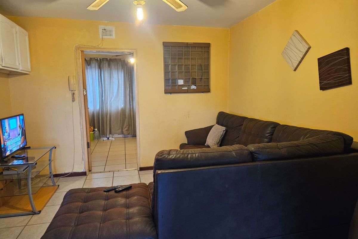 Living room featuring tiled flooring, a ceiling fan, and an intercom system, with access to an adjacent room.