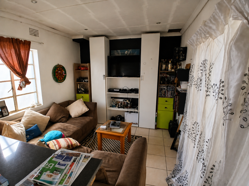 A compact living room featuring built-in storage cabinetry, tiled flooring, and natural light from a side window.