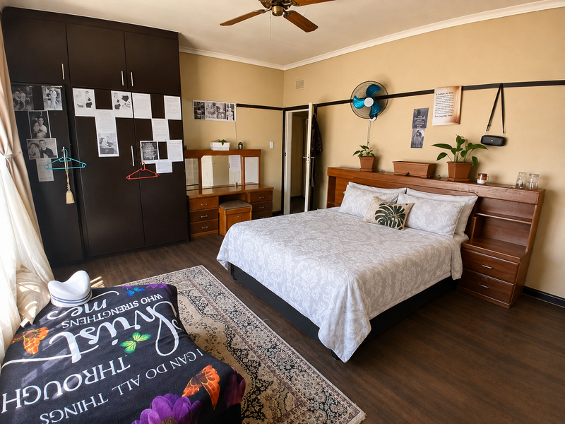 Spacious bedroom featuring dark wood-toned laminate flooring, a large built-in wardrobe, and a custom built-in headboard with integrated storage.