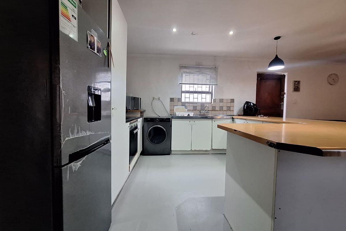 A functional kitchen featuring built-in cabinetry, a tiled backsplash, and a breakfast bar, offering a practical layout with potential for cosmetic updates.