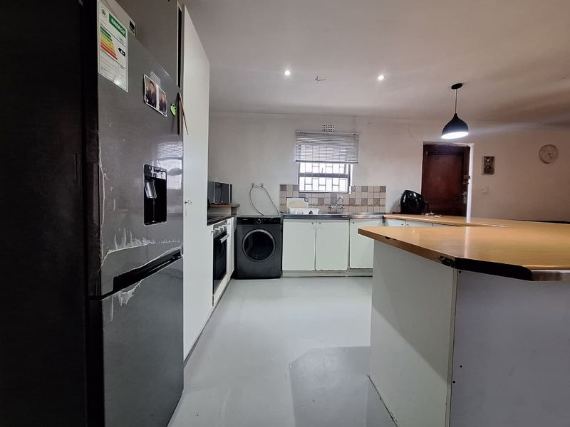 A functional kitchen featuring built-in cabinetry, a tiled backsplash, and a breakfast bar, offering a practical layout with potential for cosmetic updates.