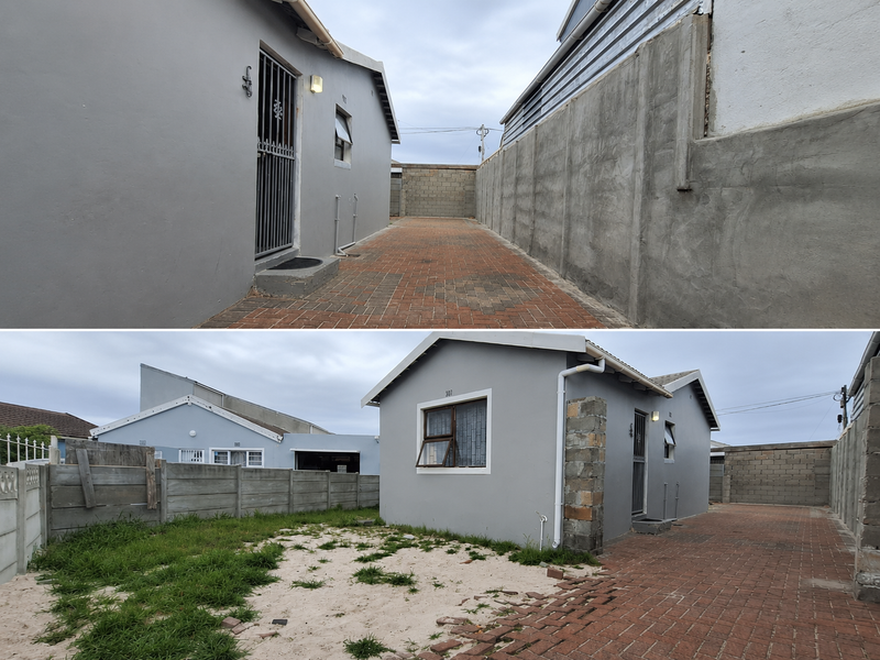 Rear exterior view of the property featuring a paved driveway, boundary walls, and an open yard area.