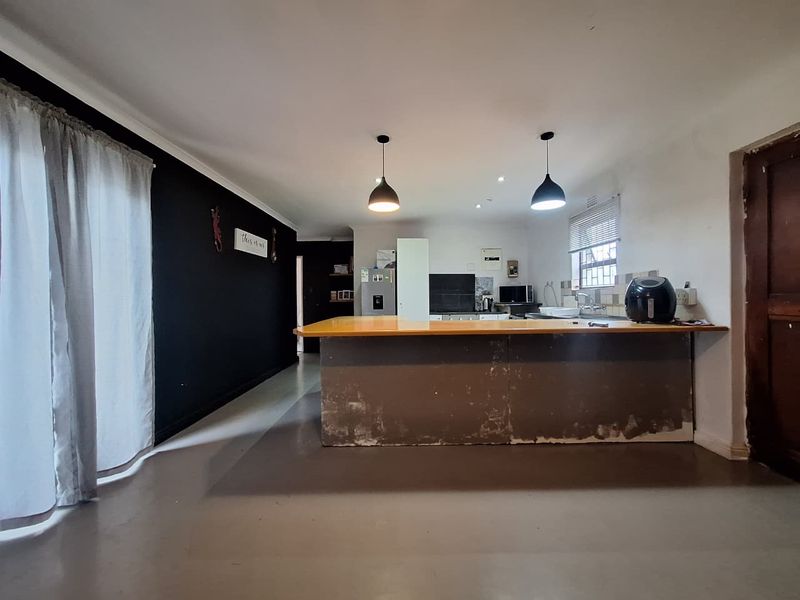 Open plan living and kitchen area featuring a central island, pendant lighting, and direct access to the exterior via a sliding door.