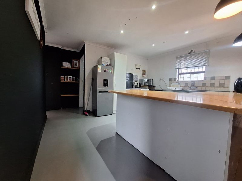 A functional kitchen featuring a central island, tiled backsplash, and built-in shelving, offering a practical layout with potential for modern cosmetic updates.