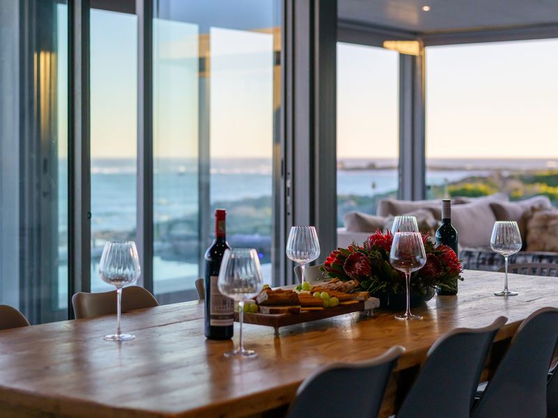 Open-plan living area featuring expansive floor-to-ceiling sliding glass doors that provide panoramic ocean views and seamless indoor-outdoor flow.