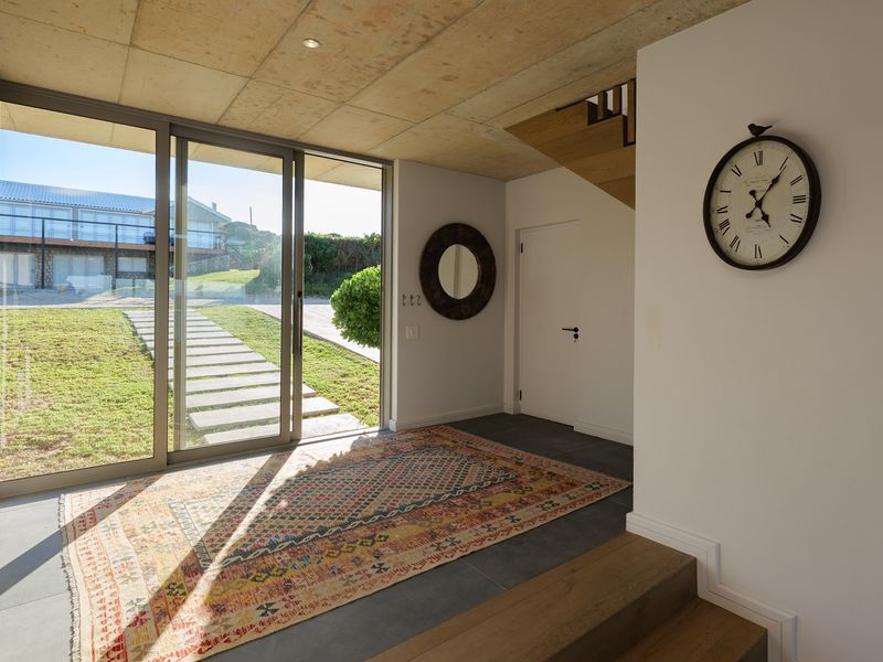 Modern entrance hall featuring an exposed concrete ceiling, tiled flooring, and large sliding glass doors providing seamless access to the garden.