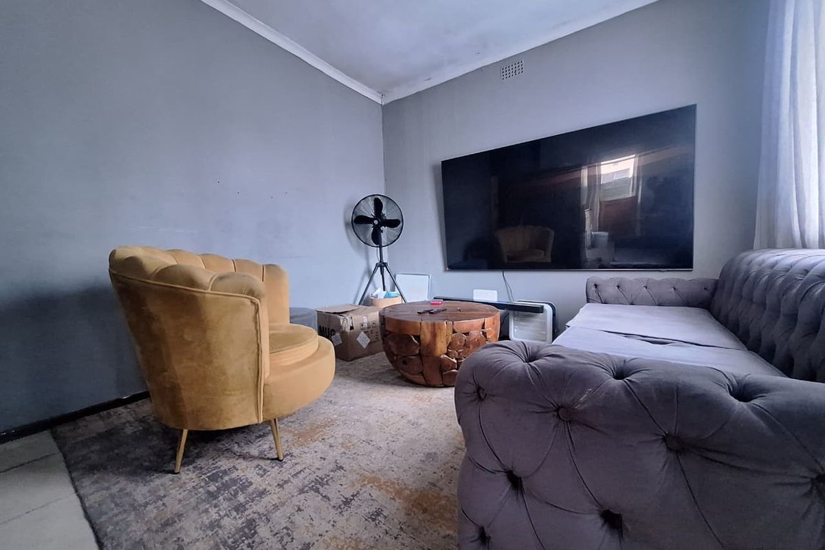 A living room space featuring neutral grey walls, coving, and a ventilation grille, providing a functional area for relaxation.