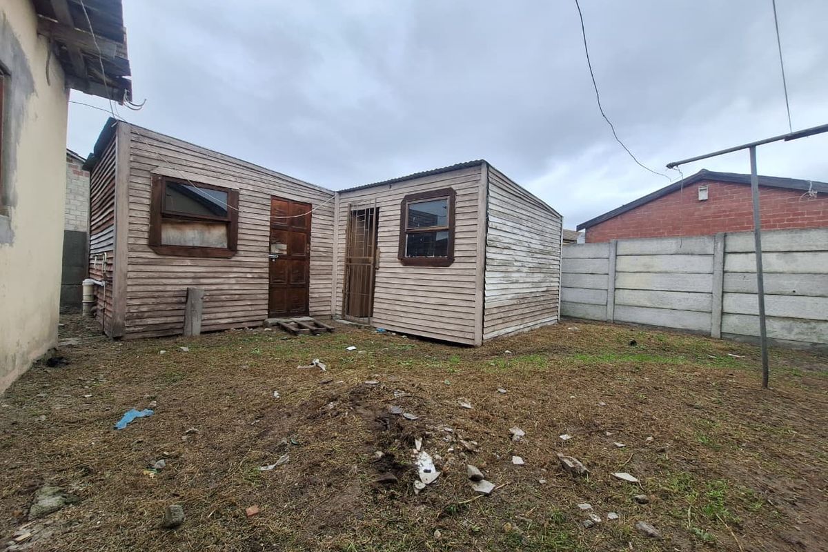 Rear view of a timber-clad outbuilding structure situated in a backyard with a precast concrete boundary wall.