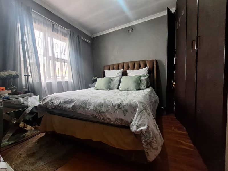 A bedroom featuring laminate flooring, a built-in wardrobe, and a window with natural light.