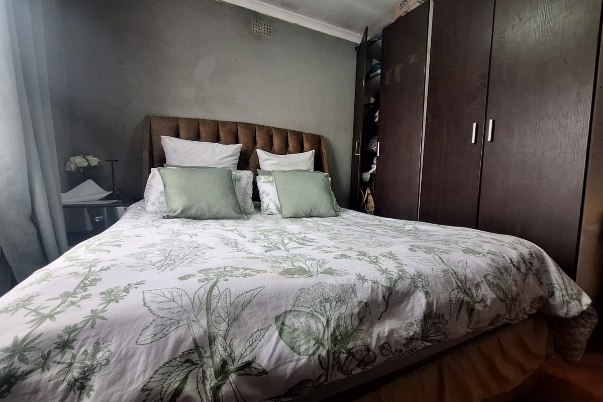 A bedroom featuring dark wood built-in cupboards and grey painted walls with coving detail.