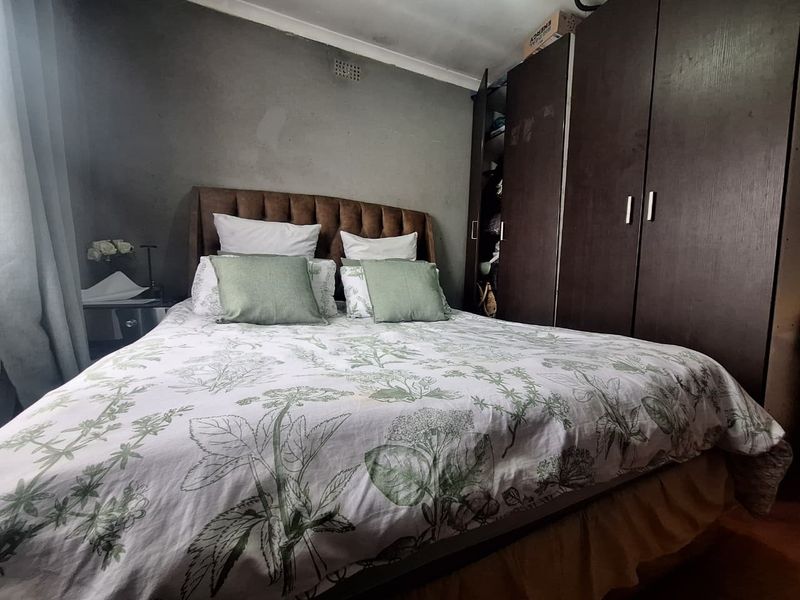 A bedroom featuring dark wood built-in cupboards and grey painted walls with coving detail.