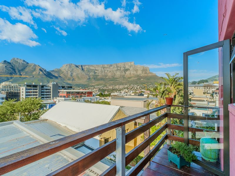 A balcony featuring timber decking and a wooden balustrade, offering expansive views of the city and Table Mountain.