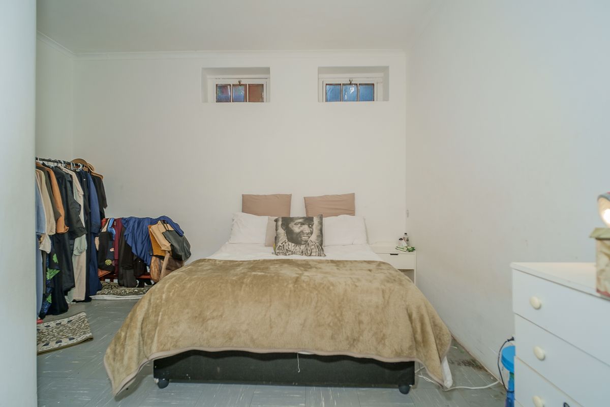 A bedroom featuring high-level windows and neutral wall finishes, requiring cosmetic updates to improve the overall condition and appeal of the space.