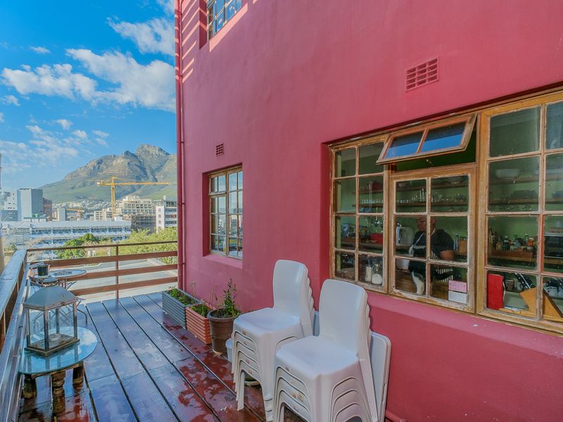 A wooden balcony featuring timber-framed windows and views of the surrounding cityscape and mountain range.