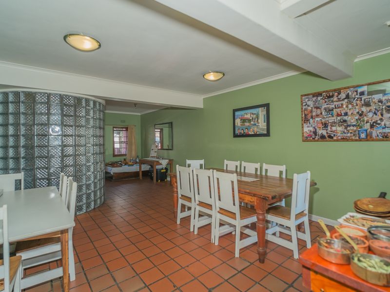 Spacious open-plan living and dining area featuring distinctive glass block wall detailing and traditional terracotta floor tiles.