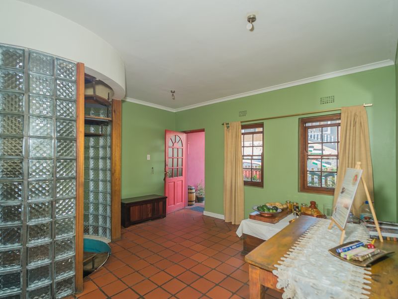 An entry area featuring terracotta tile flooring, a distinctive curved glass block wall, and timber-framed windows, providing a unique architectural character.