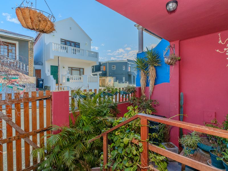 A covered outdoor patio area featuring a wooden staircase and gate, providing access to the property exterior.