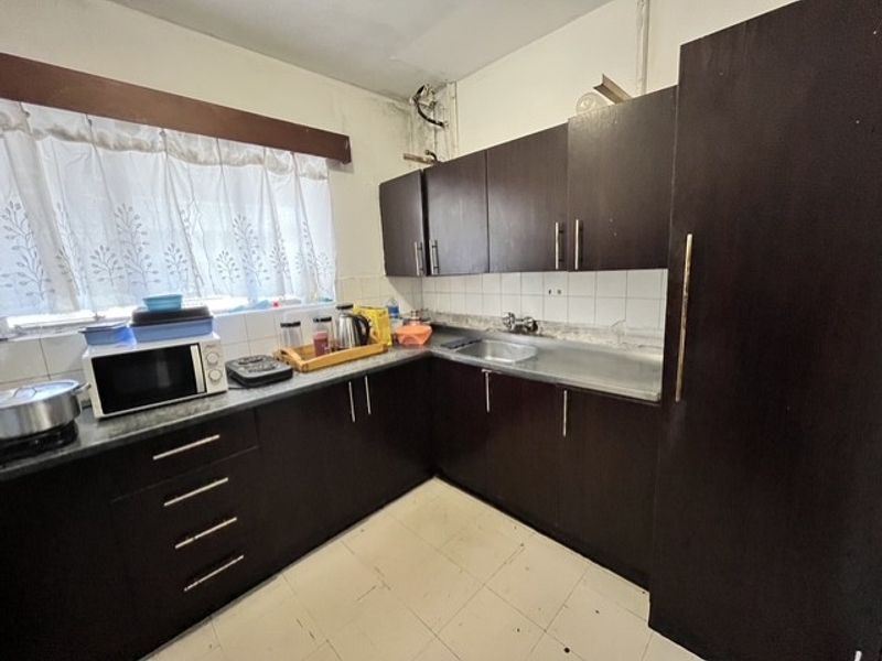 A dated kitchen featuring dark wood cabinetry, laminate countertops, and a tiled backsplash, requiring cosmetic updates and repairs to the ceiling and wall finishes.
