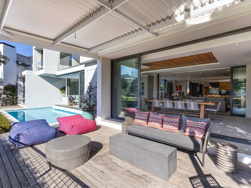 Spacious covered patio featuring timber decking, an outdoor fireplace, and seamless flow to the swimming pool and open-plan interior living area.