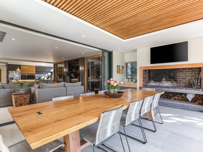 Spacious covered patio featuring a built-in fireplace, timber slat ceiling, and seamless flow into the open-plan living and kitchen area.