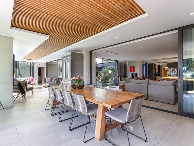 Spacious open-plan living and dining area featuring a striking slatted timber ceiling, large format floor tiles, and seamless indoor-outdoor flow through expansive sliding glass doors.