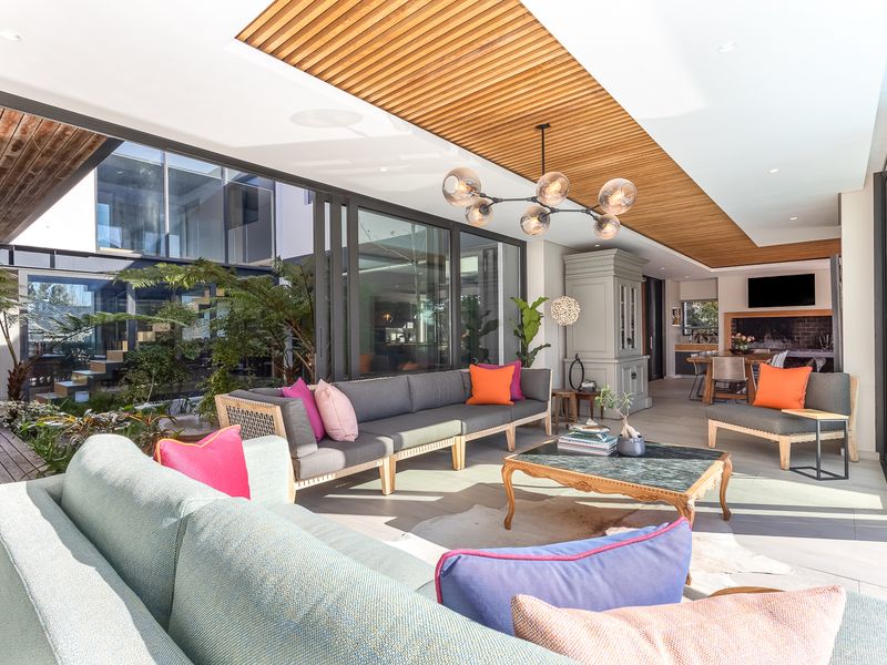 Spacious open-plan living area featuring a timber slat ceiling, large sliding glass doors opening to an internal courtyard, and a built-in fireplace.