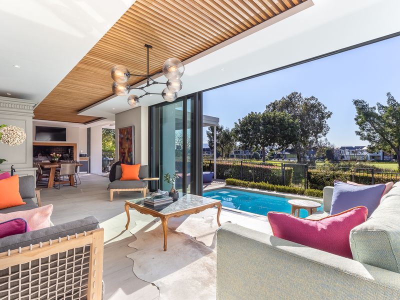 A luxurious open-plan living area featuring a slatted timber ceiling, built-in fireplace, and seamless transition to a private swimming pool and outdoor patio.