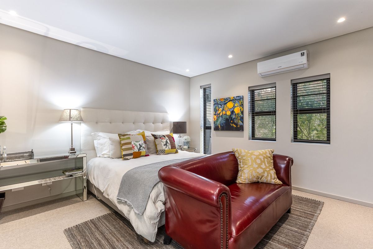 A well-maintained bedroom featuring neutral walls, carpet flooring, recessed lighting, and a wall-mounted split-system air conditioning unit.
