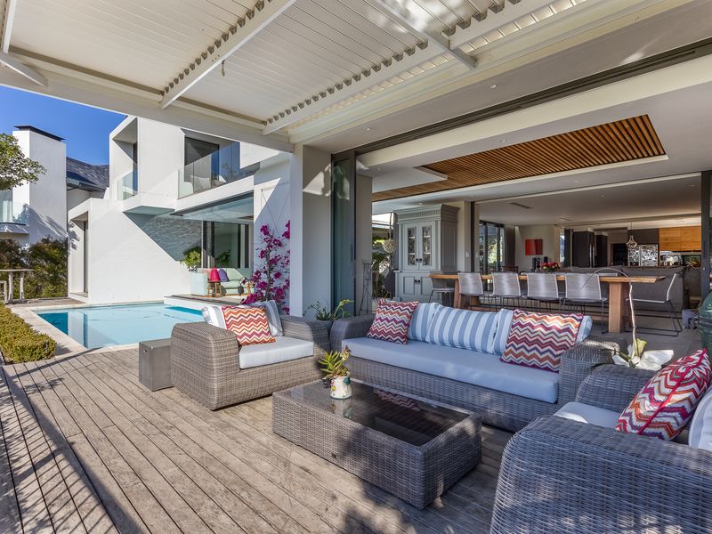 Spacious covered timber deck featuring a retractable louvered roof, seamless indoor-outdoor flow through sliding glass doors, and direct access to a private swimming pool.