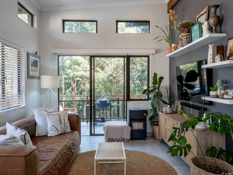 Bright living room featuring high ceilings with clerestory windows, tiled flooring, and direct access to a private balcony through sliding glass doors.
