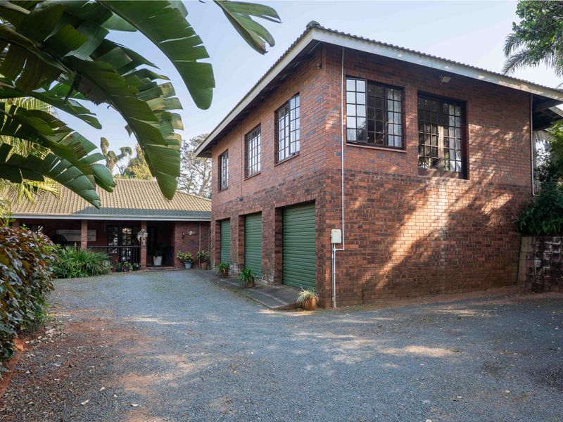 A well-maintained face brick house featuring a triple garage, tiled roof, and a spacious gravel driveway entrance.