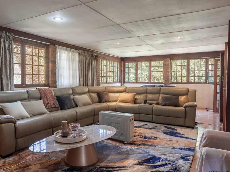 Spacious living room featuring exposed brick walls, large timber-framed windows providing ample natural light, and tiled flooring throughout.