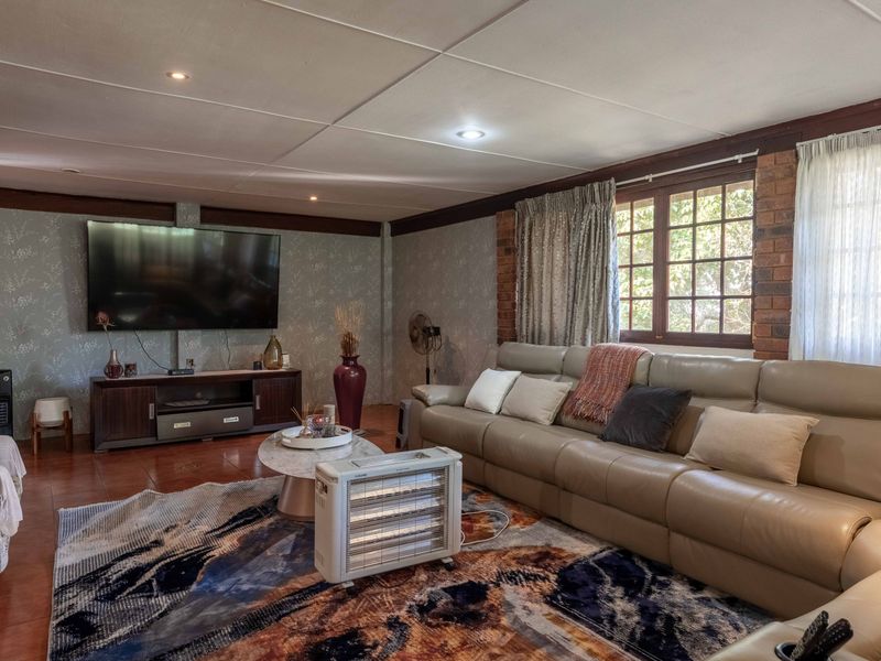 Spacious living room featuring exposed brick accents, tiled flooring, and recessed lighting, offering a comfortable and functional family space.