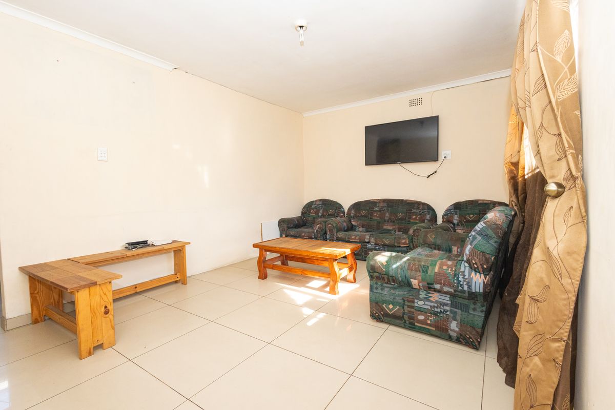 A living room featuring tiled flooring and coved cornicing, providing a functional space with potential for cosmetic updates.
