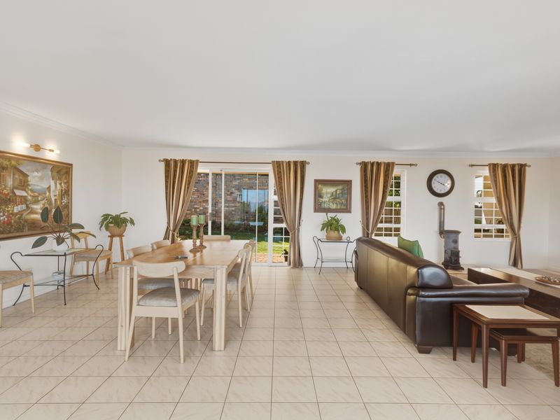 Spacious open-plan living and dining area featuring tiled flooring, a cast iron fireplace, and sliding glass doors providing access to the rear garden.