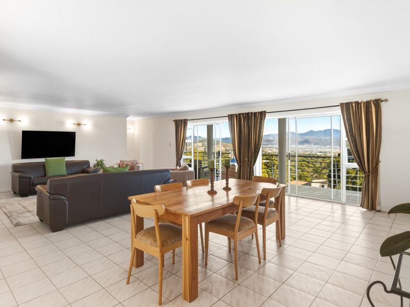 Spacious open-plan living and dining area featuring large sliding glass doors that open to a balcony with scenic mountain views.